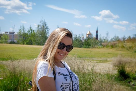 A beautiful young girl in sunglasses walks around the city. Long blonde hair flutters in the wind. Moscow Russia June 20, 2018