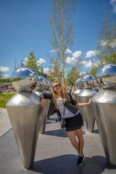 A beautiful young girl in sunglasses walks around the city. Long blonde hair flutters in the wind. Moscow Russia June 20, 2018