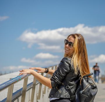 A beautiful young girl in sunglasses walks around the city. Long blonde hair flutters in the wind. Moscow Russia June 20, 2018