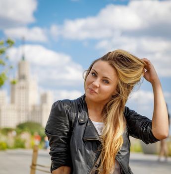 A beautiful young girl in sunglasses walks around the city. Long blonde hair flutters in the wind. Moscow Russia June 20, 2018