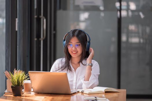 Asian girl with glasses look at laptop while doing homework making video call abroad using internet friend connection, Online learning education concept