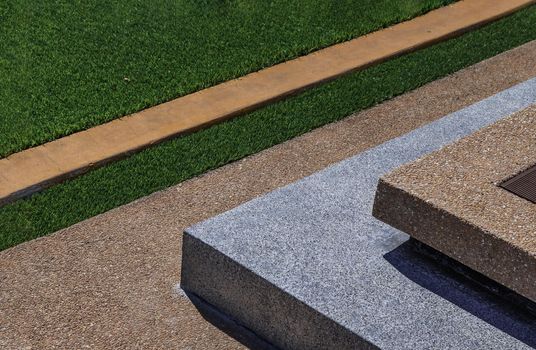 Geometry square cement floor with green grass. Abstract background. Selective focus.