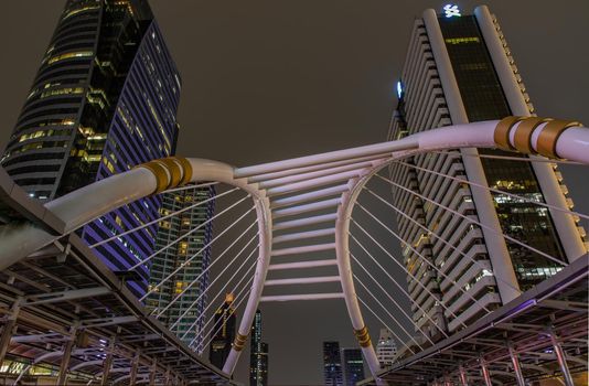 Bangkok, Thailand, Jul 03, 2020 : Skywalk bridge links bts and mrt sky train in business district with high building at dusk at Chong Nonsi skywalk. Bangkok Cityscape. Selective focus.
