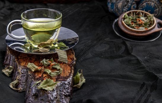 A Cup of pandan leaf tea, indian marsh fleabane plant leaves with Safflower dried (Saffron substitute) at dark background. Thai herbal plant and healthy drinks concept. Selective focus.