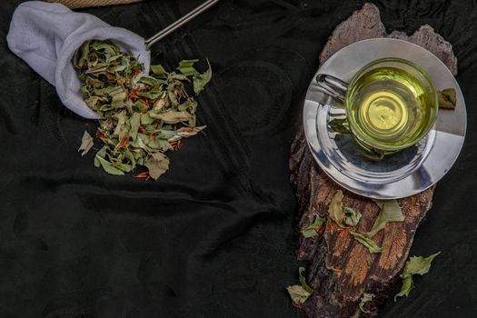 A Cup of pandan leaf tea, indian marsh fleabane plant leaves with Safflower dried (Saffron substitute) at dark background. Thai herbal plant and healthy drinks concept. Selective focus.