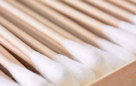 Closeup of the box full of ecological recyclable cleaning cotton swabs from recycled paper. It used for better environmental conservation. Cotton swabs on white background.