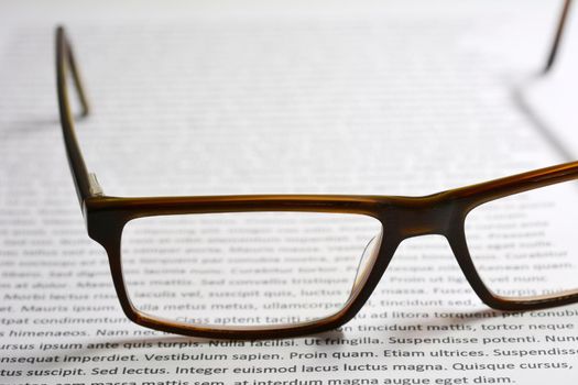 Closeup of eyeglasses on paper sheet with lorem ipsum text. 