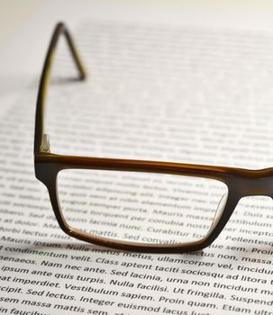 Closeup of eyeglasses on paper sheet with lorem ipsum text. 