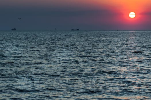 Beautiful sunset over a calm sea with a blue and orange glowing sky. Space for text, Selective focus.