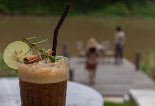 Honey lemon coffee. A glass of iced coffee mixed with honey and lemon with river view.  Refreshing summer drink concept. Copy space, Selective focus.