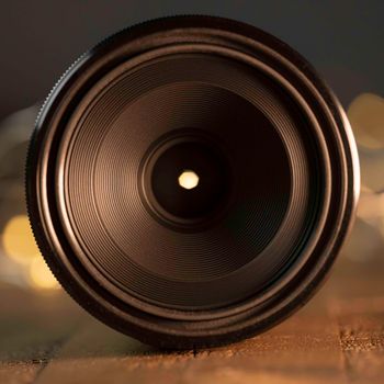 Macro camera lens, lights in background, wooden desk, macro photography. High quality photo