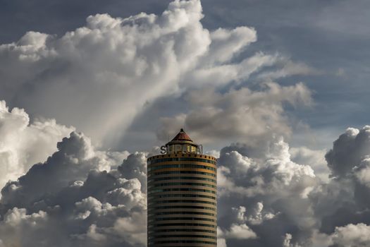 Bangkok, Thailand - Sep 24, 2020 : Angular geometric mirror cladding on a modern building with repeating structure and reflected sky and clouds. No focus, specifically.