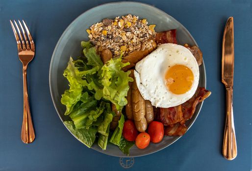 Continental breakfast with fried egg, fried sausages, vegetable on white plate. Selective focuse.