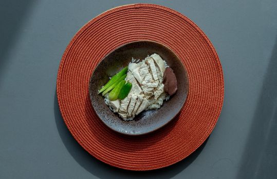 Chicken rice on the red round straw table mat. Top view, Selective focus.