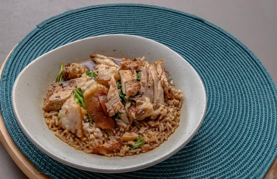 Thai stewed pork leg with rice on the blue round straw table mat. Selective focus.