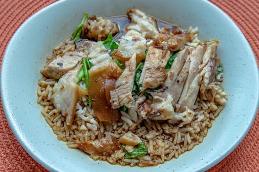 Thai stewed pork leg with rice on the red round straw table mat. Selective focus.