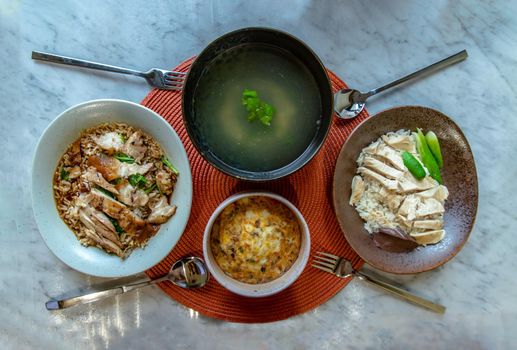Chicken rice and Thai stewed pork leg with rice, Chicken broth and Baked eggs omelet on marble table. Having Breakfast. Selective focus.