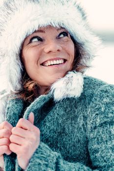 Young attractive woman happy with the falling snow in winter nature.