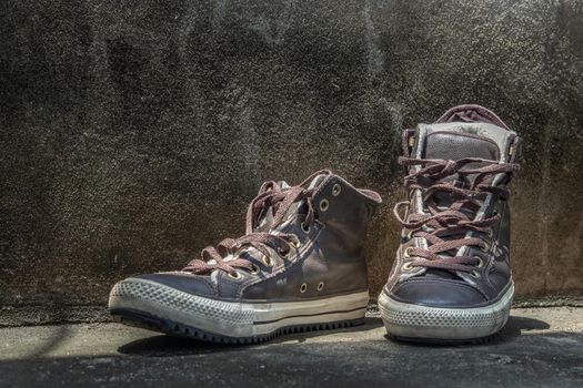 Brown Retro High Top Canvas Sneakers was placed on old cement floor. Vintage age-worn sneakers canvas shoes brown, Concept : Sometimes the long journey of life should rest. Copy space, Selective focus.