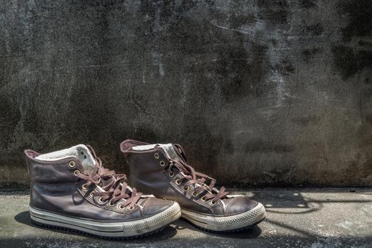 Brown Retro High Top Canvas Sneakers was placed on old cement floor. Vintage age-worn sneakers canvas shoes brown, Concept : Sometimes the long journey of life should rest. Copy space, Selective focus.