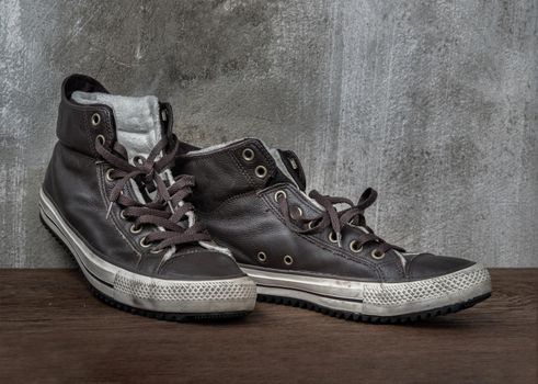 Brown Retro High Top Canvas Sneakers was placed on old wooden floor. Vintage age-worn sneakers canvas shoes brown, Concept : Sometimes the long journey of life should rest. Copy space, Selective focus.