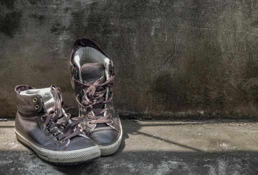 Brown Retro High Top Canvas Sneakers was placed on old cement floor. Vintage age-worn sneakers canvas shoes brown, Concept : Sometimes the long journey of life should rest. Copy space, Selective focus.