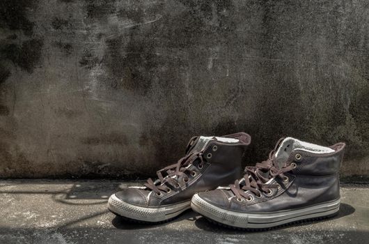 Brown Retro High Top Canvas Sneakers was placed on old cement floor. Vintage age-worn sneakers canvas shoes brown, Concept : Sometimes the long journey of life should rest. Copy space, Selective focus.