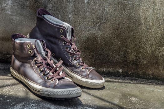 Brown Retro High Top Canvas Sneakers was placed on old cement floor. Vintage age-worn sneakers canvas shoes brown, Concept : Sometimes the long journey of life should rest. Copy space, Selective focus.
