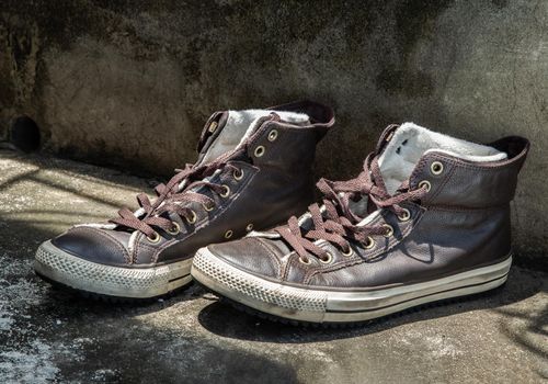 Brown Retro High Top Canvas Sneakers was placed on old cement floor. Vintage age-worn sneakers canvas shoes brown, Concept : Sometimes the long journey of life should rest. Copy space, Selective focus.