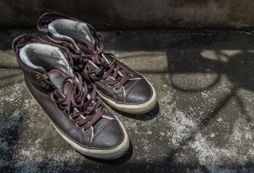 Brown Retro High Top Canvas Sneakers was placed on old cement floor. Vintage age-worn sneakers canvas shoes brown, Concept : Sometimes the long journey of life should rest. Copy space, Selective focus.