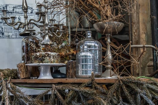Antique candlestick and Dry plant, Dried flowers, Pine cones with Glass bottle Decorate on wooden table in cafe. Vintage shop decoration idea. Selective focus.