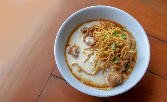 Traditional Khao Soi Recipe, Thai Northern Style Curried Noodle Soup with Chicken in white bowl. Selective focus.
