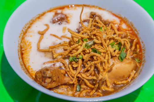 Traditional Khao Soi Recipe, Thai Northern Style Curried Noodle Soup with Chicken in white bowl. Selective focus.