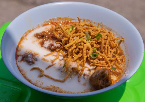 Traditional Khao Soi Recipe, Thai Northern Style Curried Noodle Soup with Chicken in white bowl. Selective focus.