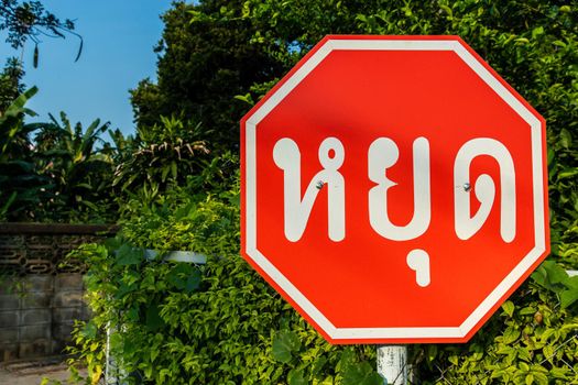 Stop sign in front of old house at the intersection in village. Selective focus.