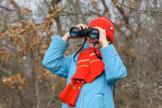 Girl enthusiastically looks through binoculars, front view, close-up