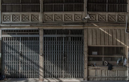 Front view of entrance of the building and old steel metal shutter and folding door gate on old industrl building. No focus, specifically.