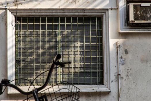 Steel window frame and the vent shade side on wall of an old house. Selective focus.