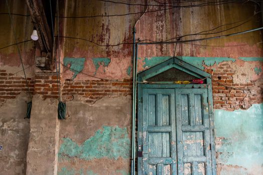 Old wood vintage door on the old wall with visible bricks texture was left to deteriorate over time. Traditional Architecture style, Selective focus.