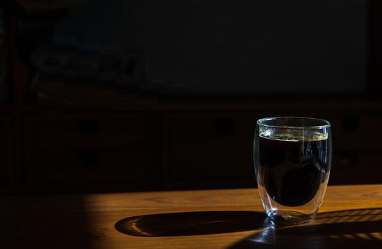 Black coffee in glass cup on wooden table in the room. Coffee style, Copy space, Selective focus.