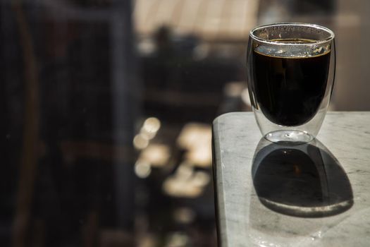 Black coffee in glass cup on marble table in the morning. Coffee style, Copy space, Selective focus.