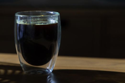 Black coffee in glass cup on wooden table in the room. Coffee style, Copy space, Selective focus.