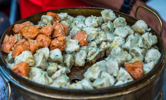 'Shumai' (Shaomai) or Kanom Jeeb' a 'Dim Sum' Chinese traditional steamed dumplings food with shrimp and pork inside in metal tray for sale at street market. Traditional breakfast asian styles. Selective focus.