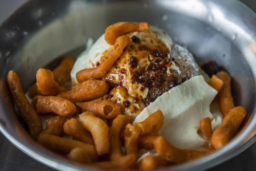 Close-up of Shaved ice soft tofu with ginger syrup topped with deep-fried dough sticks (pa tang ko) in Silver bowl. Good for health. Selective focus.