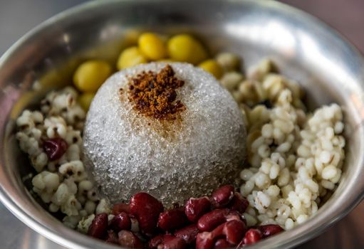 Close-up of Grass Jelly and cold red beans, ginkgo, millet served with ice in Silver bowl. Thai dessert, Very popular street food in Thailand. Selective focus.