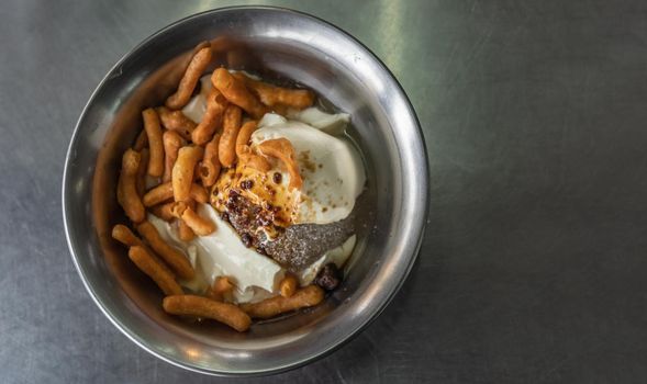 Shaved ice soft tofu with ginger syrup topped with deep-fried dough sticks (pa tang ko) in Silver bowl. Good for health. Top view. Copy space, Selective focus.