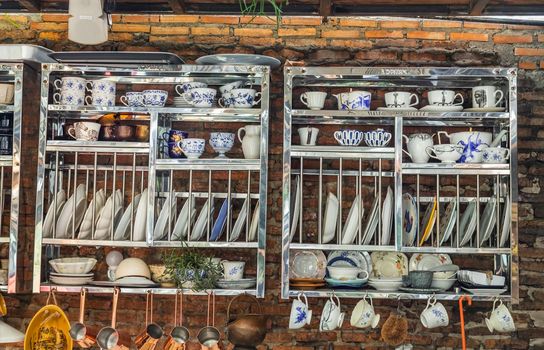 Luxury ceramic tableware on stainless shelves on the red brick wall. No focus, specifically.