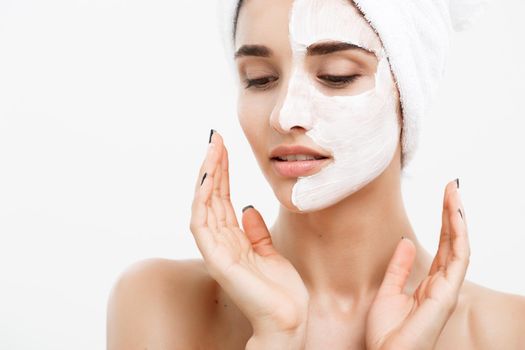 Beauty Skin Care Concept - Beautiful Caucasian Woman Face Portrait applying cream mask on her facial skin white background