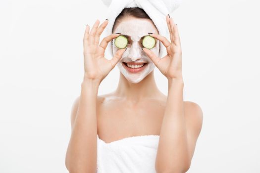 Beauty Youth Skin Care Concept - Portrait Beautiful Caucasian Woman apply cream and holding fresh cucumber in front of her face.Isolated over white background