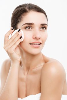 Beauty Skin Care Concept - Beautiful woman cleaning her face with cotton swab - over white background and smiling